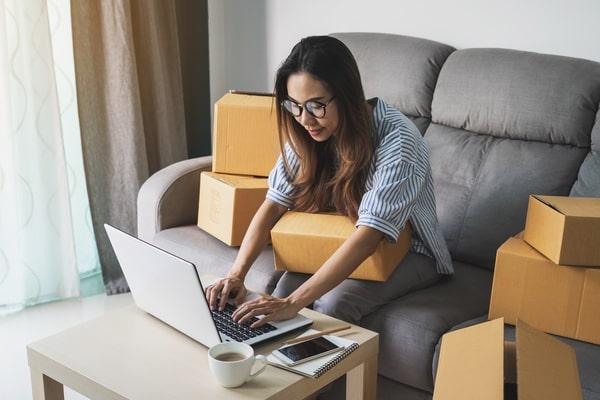 photo of a woman working on a laptop with packages